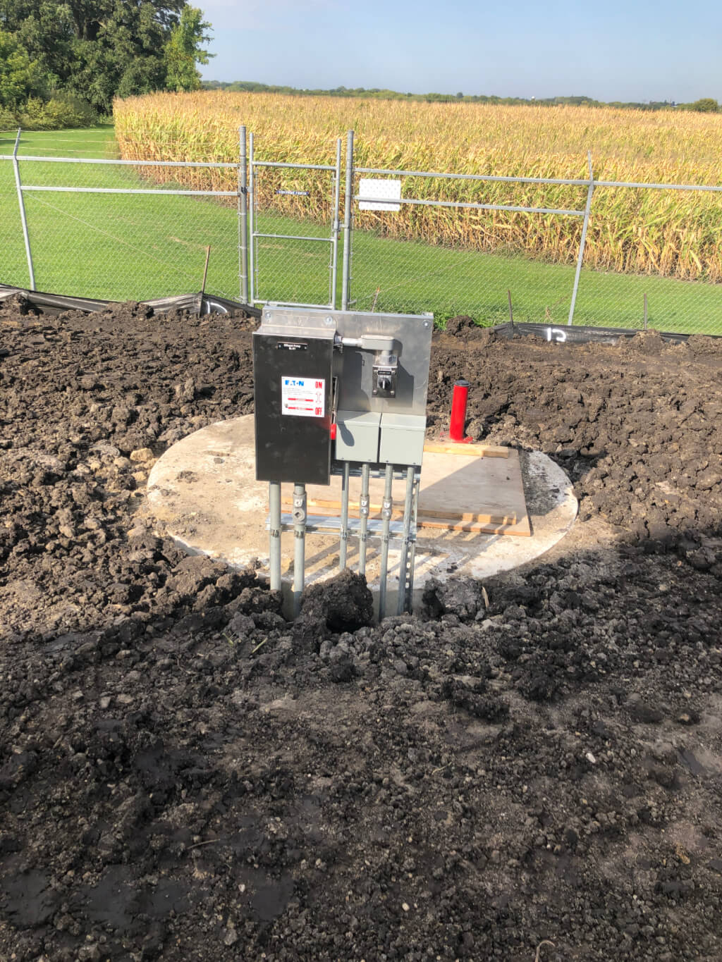 Water treatment controls protruding from dirt in front of a cornfield